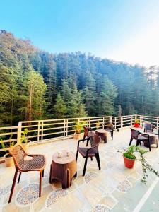 a patio with chairs and tables in front of a forest at Decent Stays Rooms and Apartments in Shimla
