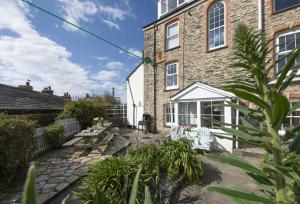 a brick house with a patio with chairs and tables at Trethoway in Port Isaac