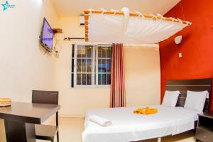 a room with two beds and a table and a desk at Salama Hôtel Majunga in Mahajanga