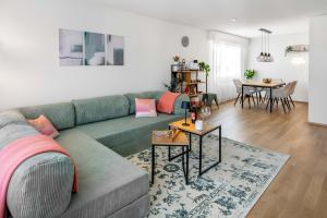 a living room with a green couch and a table at BASEKAMP Horizon I Luzern I Familie I Pilatus in Lucerne