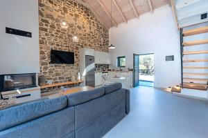 a living room with a blue couch and a stone wall at Twin Olive Villas in RhodesRhodes