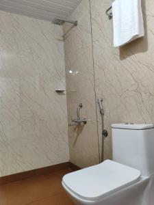 a bathroom with a white toilet and a shower at Rays of Bliss in Mananthavady
