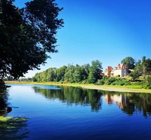 a river with trees and a house in the background at A La Bruyère in Saint-Martin-du-Lac