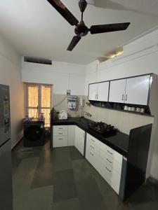 a kitchen with white cabinets and a ceiling fan at Leos Inn in Pune