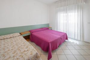 a bedroom with a bed with a pink blanket at Residenza Stella X in Bibione