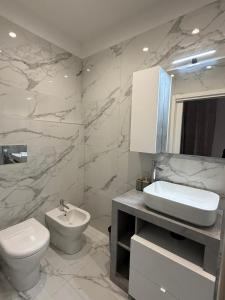 a white bathroom with a toilet and a sink at Elled-home in Misterbianco