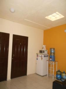 a kitchen with a white refrigerator and orange walls at Hotel Posada del Ángel in Villahermosa
