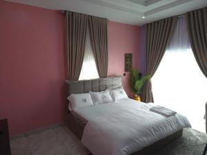 a bedroom with a large bed with pink walls at House 27 Alpha in Idu