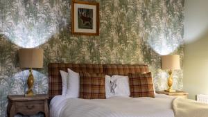 a bedroom with a bed with two lamps on tables at The Plough in Alnwick