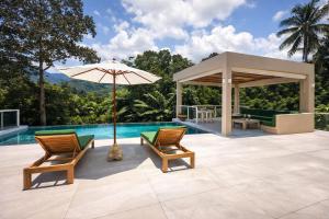 a patio with two chairs and an umbrella next to a pool at Jungle Home in Koh Samui