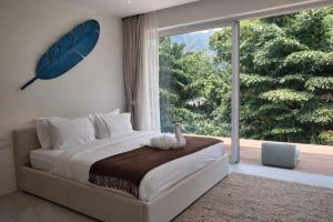 a bedroom with a bed and a large window at Jungle Home in Koh Samui +22 photos