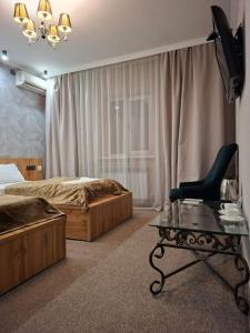 a bedroom with a bed and a chair and a glass table at Hotel Mardin in Almaty