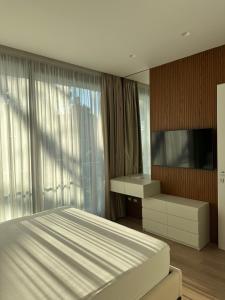 a bedroom with a bed and a tv and curtains at Azure Pool Villa in Lalzit Bay