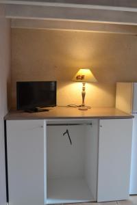 a lamp sitting on top of a desk with a tv at Tamaris in La Jarrie
