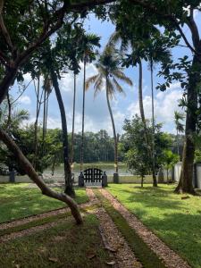 a park with palm trees and a bench at The River House in Cochin