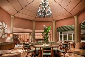 a restaurant with tables and chairs and a chandelier at Grand Hotel Las Dunas, Autograph Collection in Estepona