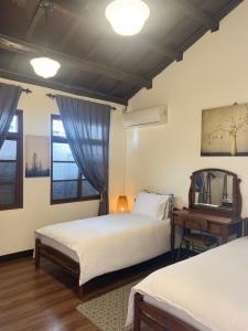 a bedroom with two beds and a table and a mirror at 海軍官邸眷村民宿 in Nan-men