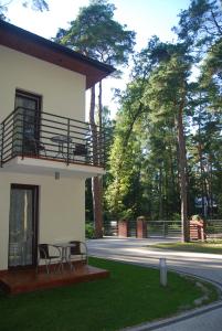 a building with two chairs and a table in the grass at Villa Veell - tylko 4 minuty od pięknej szerokiej plaży in Pobierowo