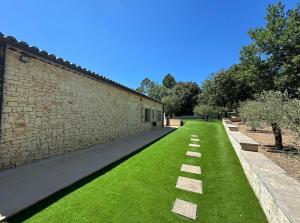 a garden with green grass next to a brick building at Villa Bon Cavai in Mornas