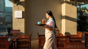 a woman holding a tray of food in a patio at Mitsis La Vita in Rhodes Town +24 photos