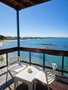 two chairs and a table on a balcony with the ocean at Hoedjiesbaai Hotel in Saldanha