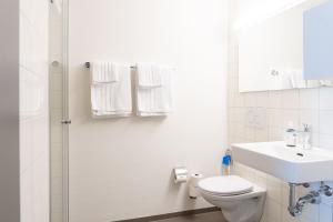 a white bathroom with a toilet and a sink at Gästehaus Hunziker in Zurich +29 photos