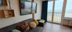 a living room with a couch and a large television at Zeezicht Studio Alisa in Blankenberge +21 photos