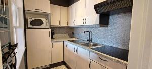 a small kitchen with a sink and a microwave at Zeezicht Studio Alisa in Blankenberge