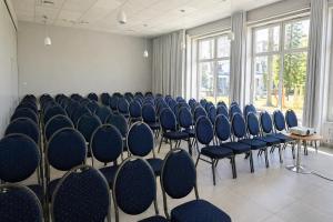 an empty room with blue chairs and windows at Albatros Medical SPA in Mielno