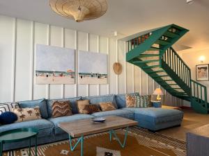 a living room with a blue couch and a staircase at Sea You Beach House in Rogowo