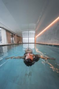 a man swimming in a swimming pool with a shark at Zin Park alpine suites and SPA in San Candido