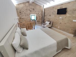 a bedroom with a large white bed and a tv at Abrigo da Serra - Soajo Mountain Lodge in Adrão