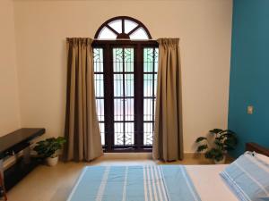 a bedroom with a large window with curtains at Aurena Stays Varkala in Varkala +6 photos