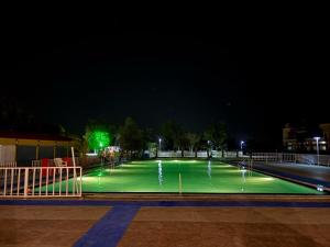 a tennis court lit up at night with a fountain at Hotel Goram Garh Resort in Pāli