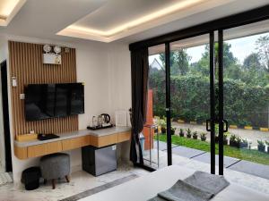 a bedroom with a desk with a television and a window at Moya Villa & Resto in Cihideung