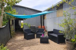 a patio with black chairs and a blue canopy at Une étape tranquille in Drefféac