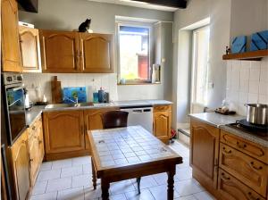 a kitchen with wooden cabinets and a cat sitting on the window at Une étape tranquille in Drefféac