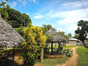 a garden with tables and chairs and a thatch hut at HOTSPOT inn - Malindi in Malindi