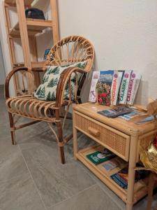 a wicker chair next to a table with a book shelf at I Giardini del Caramante in Soverato Marina