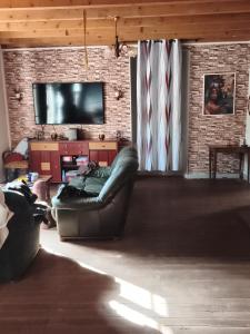 a living room with a couch and a flat screen tv at Chambre pèlerinage in Saint-Hilaire-la-Palud