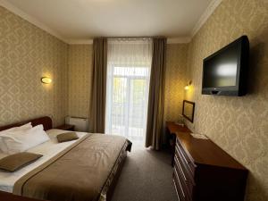 a hotel room with a bed and a flat screen tv at Курортний Готель Золота Корона in Truskavets
