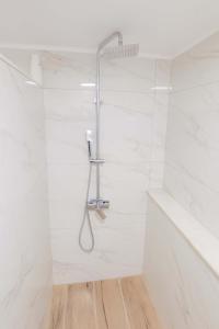 a shower in a white bathroom with white tiles at Thea Villa in Kokkinos Pirgos