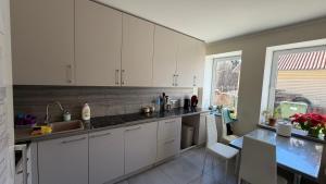 a kitchen with white cabinets and a table at DelMar in Klaipėda