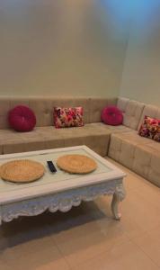 a living room with a couch with pillows and a coffee table at Alnozhah in Ḑurumā