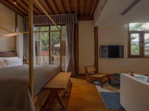 a bedroom with a bed and a table and a tv at PURE Hotel Lijiang in Lijiang