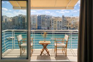 a balcony with a table and chairs and a view of the water at Seafront-Top Location-Close To Shops & Restaurants in St. Julianʼs