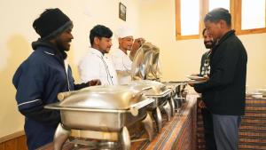 a group of men standing around a buffet in a kitchen at Hotel DE Suzain-Leh in Leh