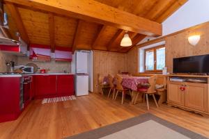 a kitchen with red cabinets and a table with chairs at El Feral - Mansarda in Selva di Cadore