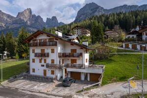 a house in the mountains with a car parked in front at El Feral - Mansarda in Selva di Cadore