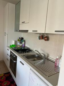 a white kitchen with a sink and a stove at Dimora Dafne in Policoro +4 photos